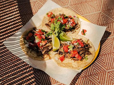 Three tacos with beef and peppers in the sun.